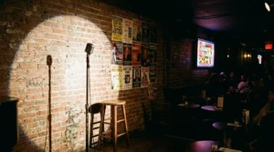 Empty NYC comedy club stage with single microphone exposed brick wall and spotlight