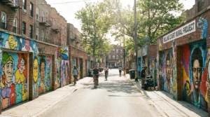Long perspective of a residential Queens street with murals on every garage door